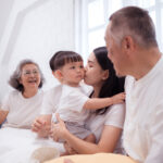 asian mom holding a toddler boy with happy grandma and grandpa sitting next to them
