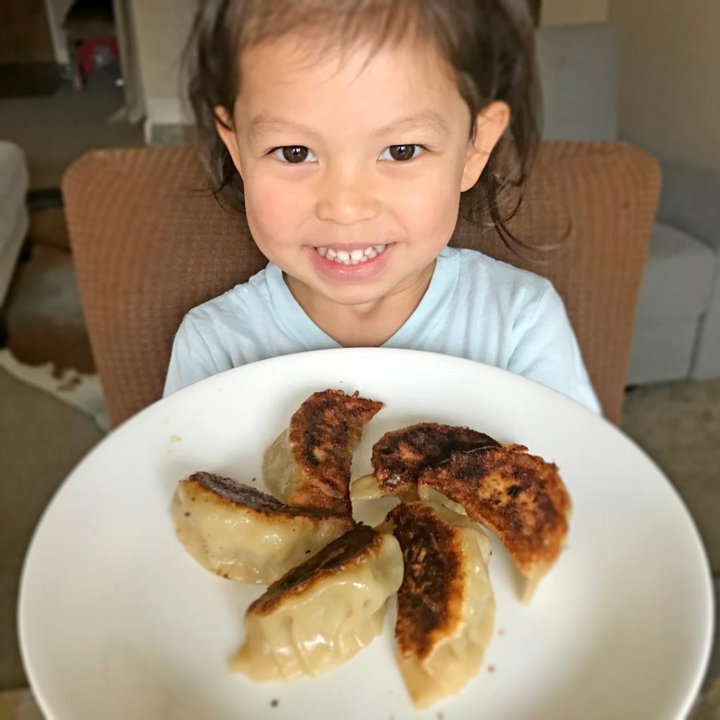 girl holding a plate of potstickers